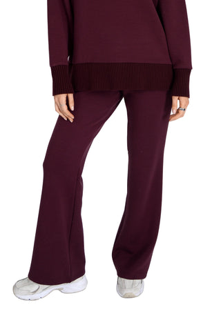 Person wearing a maroon sweater and pants on a white background