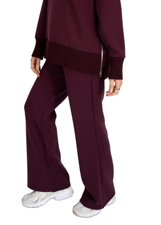 Person wearing a burgundy outfit with wide-leg pants and a matching top on a white background