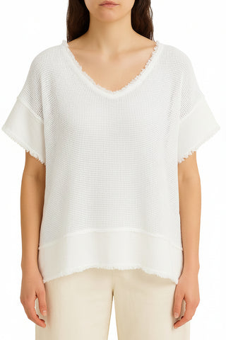 Woman wearing a light beige mesh top and pants against a white background