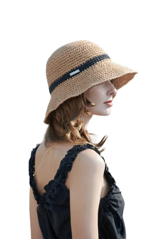 Woman wearing a straw hat with a black band outdoors