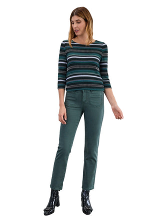 Woman wearing a striped sweater and green pants against a white background