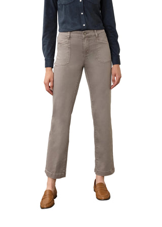 A model wearing light gray straight-leg jeans, a navy blue button-down shirt, and brown leather loafers, standing against a neutral studio backdrop.