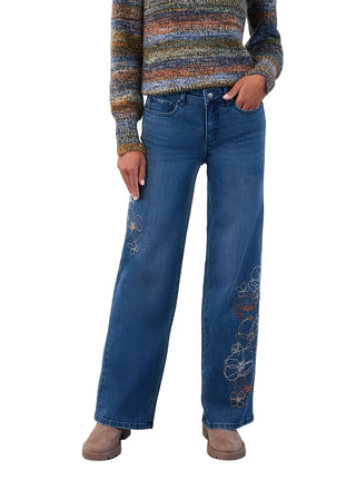Person wearing a colorful striped sweater and blue jeans with floral embroidery on a white background