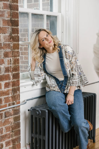 Woman sitting on a radiator against a brick wall