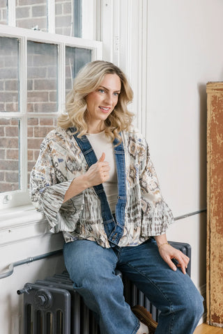 Woman sitting on a radiator in a room with a window and white walls