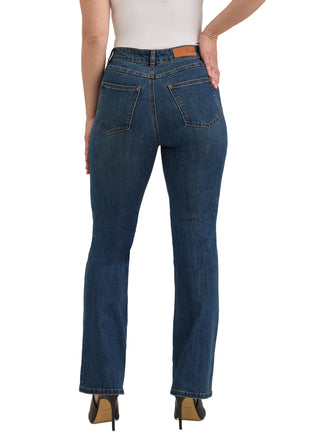 Rear view of a model wearing dark blue straight-leg jeans with a brown leather patch on the waistband, paired with a white top and black heels, against a light gray studio background.