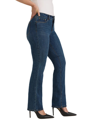 A model wearing a pair of dark blue flare jeans, styled with a white top and black pointed-toe heels, shown from the waist down against a light gray studio background.