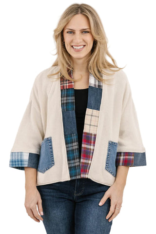 Woman wearing a patchwork jacket with plaid patterns on a plain background