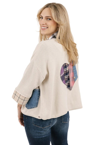 Woman wearing a cream jacket with plaid accents on a white background