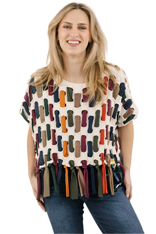 Woman wearing a colorful patterned top with tassels on a white background