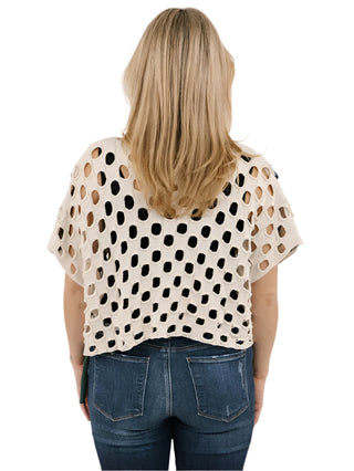 Woman wearing a polka dot top and jeans on a plain background