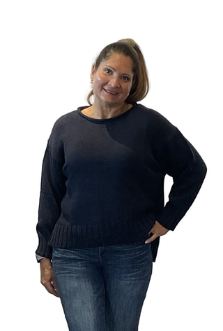 Woman wearing a black sweater and blue jeans against a white background