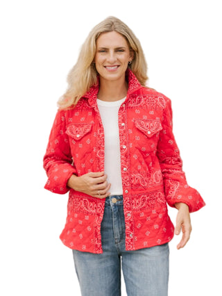 Woman wearing a red bandana-patterned jacket against a beige wall.