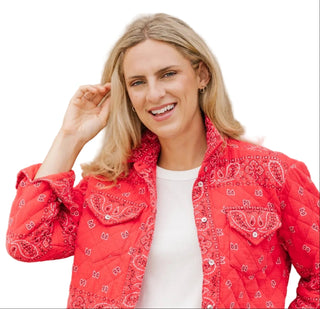 Woman wearing a red bandana-patterned jacket against a beige wall.