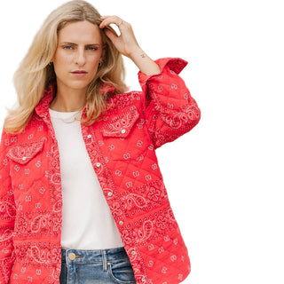 Woman wearing a red bandana-patterned jacket against a beige wall.