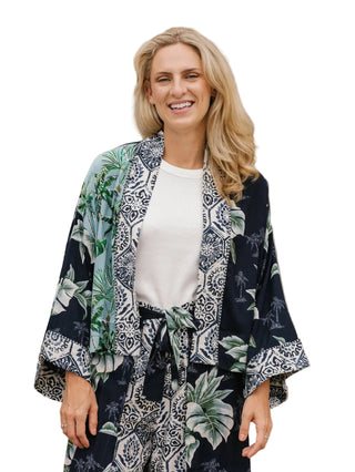 Woman wearing a navy blue kimono with white patterns against a beige stone wall.