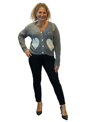 Woman wearing a gray sweater with heart patterns in front of an 'Anne's on the Avenue' sign.