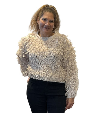 Woman wearing a textured beige sweater against a white background