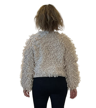 Person wearing a textured beige sweater against a white background