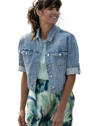 Woman wearing a denim jacket over a tie-dye outfit against a neutral background