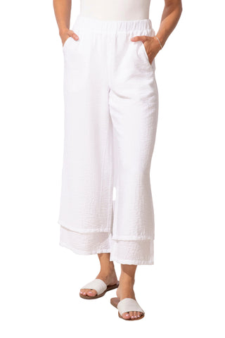 Person wearing white pants standing on a light wooden floor with a white background