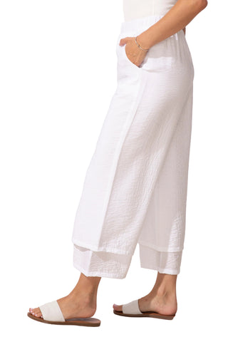 Person wearing white pants and sandals on a light background