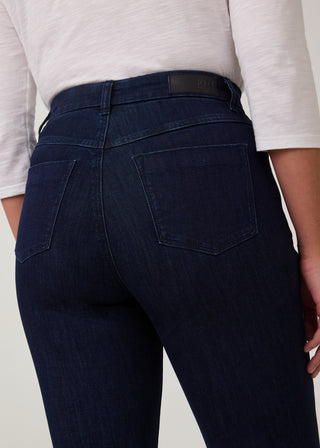 Person wearing dark blue jeans with a plain background