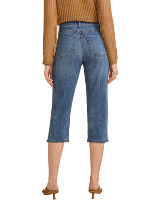 Person wearing blue jeans and a brown top on a beige background