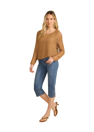 Woman wearing a brown sweater and blue jeans on a beige background