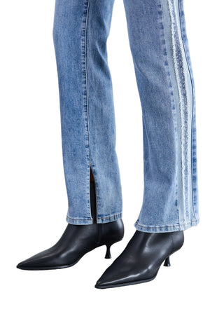 Person wearing blue jeans with a side stripe and black high-heeled boots on a light gray floor.