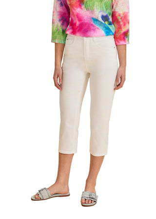Person wearing a colorful tie-dye shirt and white pants on a beige background