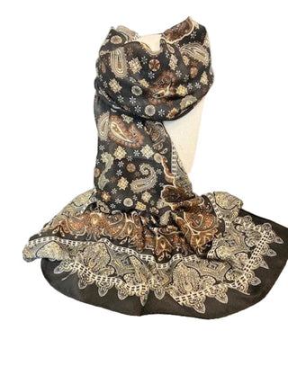A black scarf with an intricate brown, beige, and gold paisley pattern draped over a white dress form on a gray countertop.