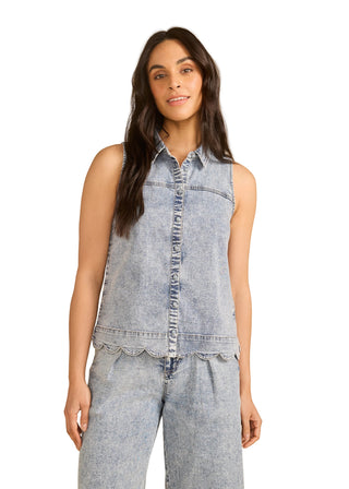 Woman wearing a sleeveless denim shirt and jeans on a beige background