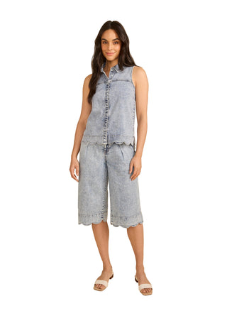 Woman wearing a sleeveless denim top and shorts on a beige background