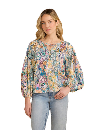 Woman wearing a floral blouse and jeans against a beige background