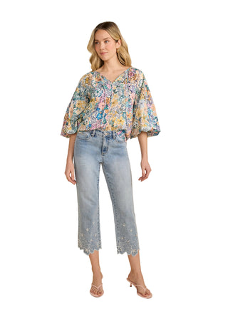 Woman wearing a floral blouse and light blue jeans on a beige background