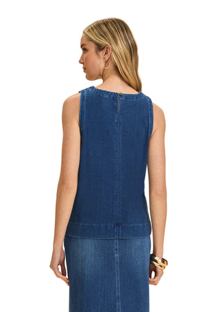 Woman wearing a blue denim dress against a beige background