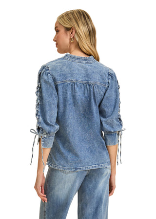 Woman wearing a blue denim jacket with tied sleeves on a beige background