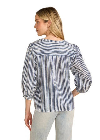 Woman wearing a blue and white striped blouse against a beige background