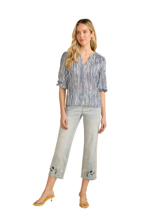 Woman wearing a striped shirt and light jeans on a beige background