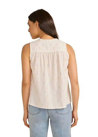Woman wearing a sleeveless cream top with subtle pattern against a beige background