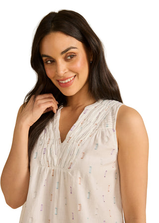 Woman wearing a light-colored sleeveless top with a subtle pattern against a beige background