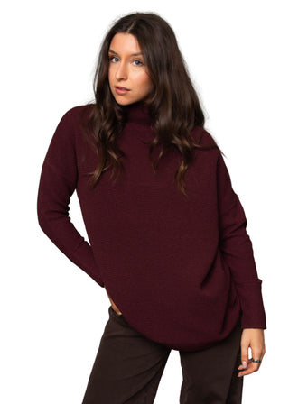 Woman wearing a burgundy sweater against a gray background