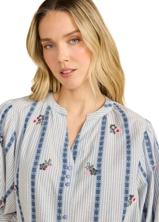 Woman wearing a striped shirt with floral embroidery on a beige background