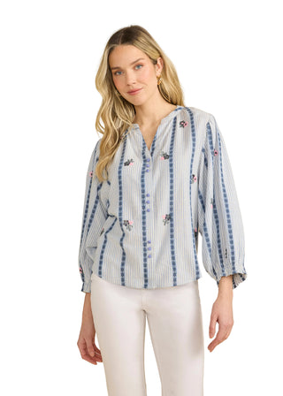 Woman wearing a striped blouse with decorative elements on a beige background