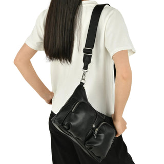 Person wearing a black shoulder bag on a plain background