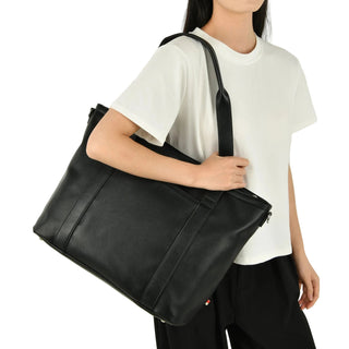 Person holding a black leather bag against a plain background