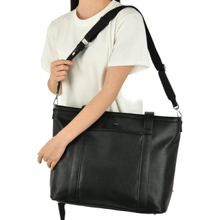 Person holding a black leather bag with a plain background