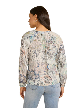 Woman wearing a floral blouse and jeans against a beige background