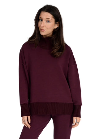 Woman wearing a burgundy sweater and pants on a white background
